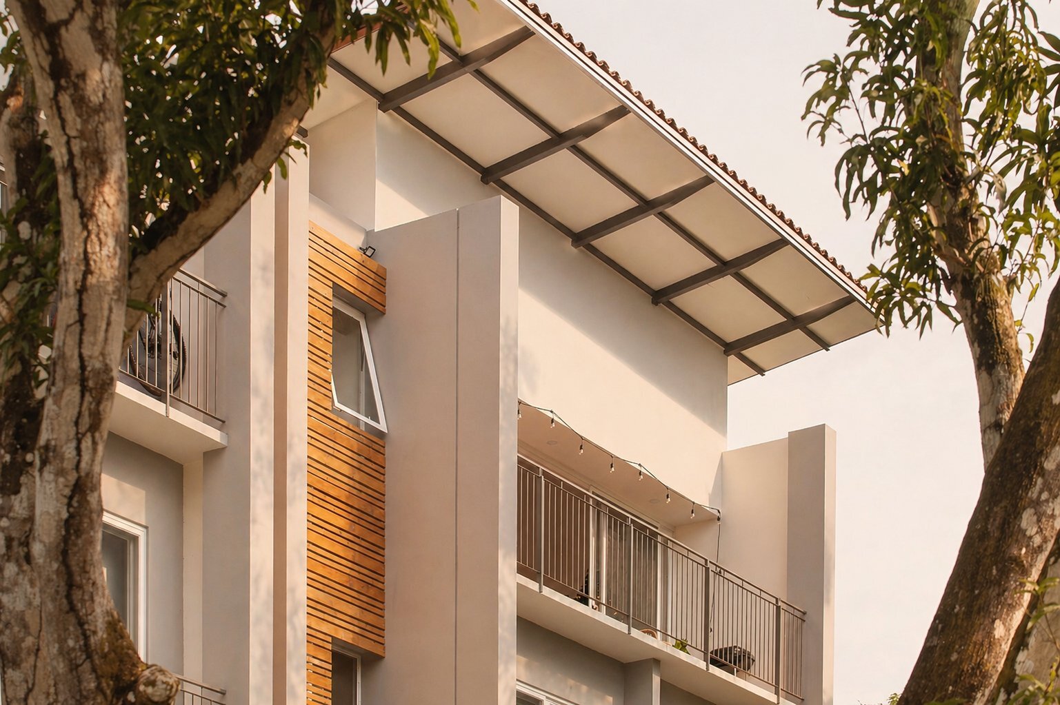 Hermosa Salvaje at golden hour — wood slat detail and balconies framed by mango trees